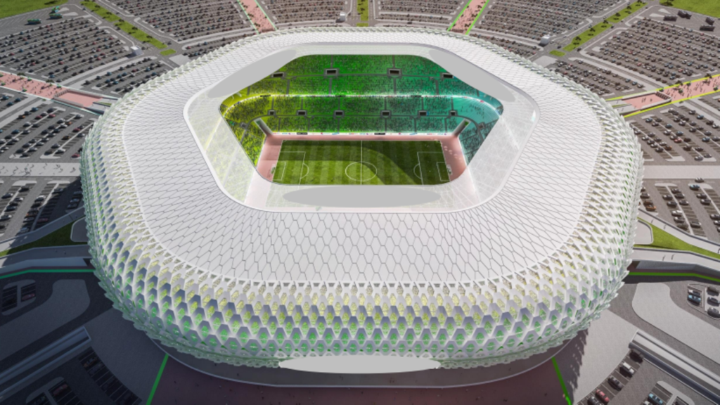 Aerial View of a Circular Stadium with a White Lattice Outer Shell and a Green Football Pitch Inside Surrounded by Parking Lots